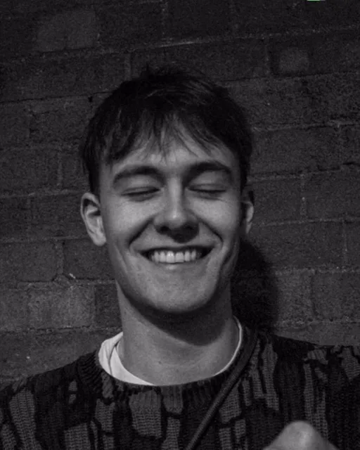 Joe Flynn, laughing, against a brick wall